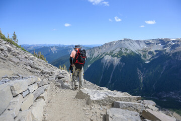 Fototapeta premium Three people hiking Sunrise Trail with rolling mountains in the distance. Mt Rainier National Park. Washington State.