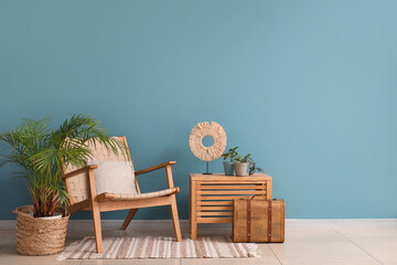 Comfortable armchair and houseplant near blue wall