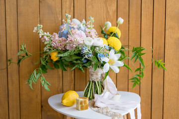 Lemon and a wooden box with rings stand next to the bride bouquet on a stool against the wall