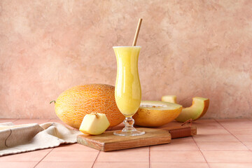 Wooden board with glass of tasty melon smoothie on pink tile table