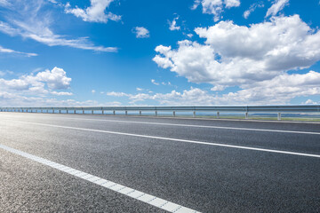 Asphalt highway road and blue sky with white clouds background