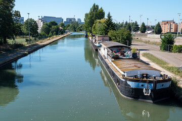 boat is floating on a river with a city in the background. The water is calm and the sky is clear. Strasbourg, France