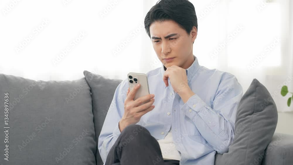 Aufkleber スマホ、スマートフォン、アプリ、SNS、メール、考える、疑問、不満、男性、日本人、ソファー、リビングルーム、自宅、室内、不安、心配、悩む、悩み、困る、迷う、通販、ニュース、カジュアル、タッチ、操作、DX、デジタル、データ、動画、疑う、詐欺、コピースペース、シリアス、不信感、投稿、戸惑う、インターネット、オンライン、web、トラブル、情報、部屋、ライフスタイル、投資、ゲーム、不正、ウイルス、なりすま