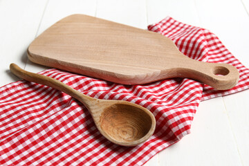Wooden board with spoon and napkin on white wooden kitchen table