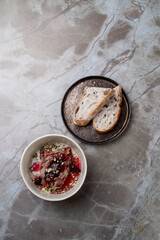 A delicious dish rests elegantly in a bowl, enhanced by colorful garnishes, accompanied by slices of artisan bread. The atmosphere speaks of fine dining and meticulous attention to detail