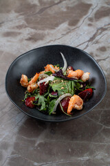 A delicious shrimp salad awaits at a charming European restaurant, showcasing fresh greens, tender shrimp, and vibrant berries, perfect for an elegant culinary experience