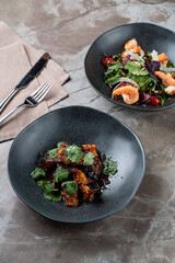 A delightful culinary experience unfolds with two stunning dishes featuring vibrant greens and expertly cooked proteins, beautifully presented in elegant bowls at a cozy restaurant setting