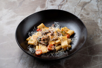 Savor the rich flavors of freshly crafted pasta adorned with succulent ingredients, artfully presented on a sleek black plate in a chic European restaurant atmosphere