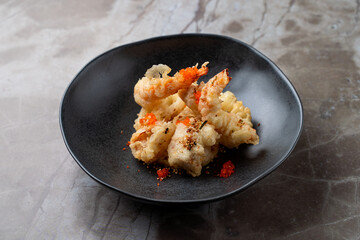 Enjoying a delicious plate of tempura shrimp at a European-style restaurant during an elegant evening dinner with friends, showcasing culinary craftsmanship and fresh ingredients