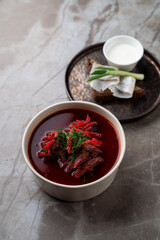At a charming restaurant, guests enjoy a hearty bowl of vibrant beet soup topped with fresh herbs. Accompanied by toasted bread and a dollop of sour cream, this dish embodies warmth and comfort