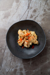 Delight in a beautifully plated dish featuring succulent seafood, adorned with a spicy sauce. This culinary creation is set against an elegant backdrop, perfect for an intimate dining experience