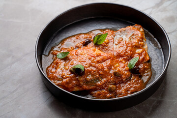 Experience a sumptuous meal featuring perfectly cooked fish smothered in a vibrant tomato sauce, garnished with fresh herbs. Perfectly served in an upscale setting, it invites diners to indulge
