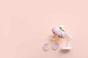 Composition with mini desk lamp and beautiful flower on color background