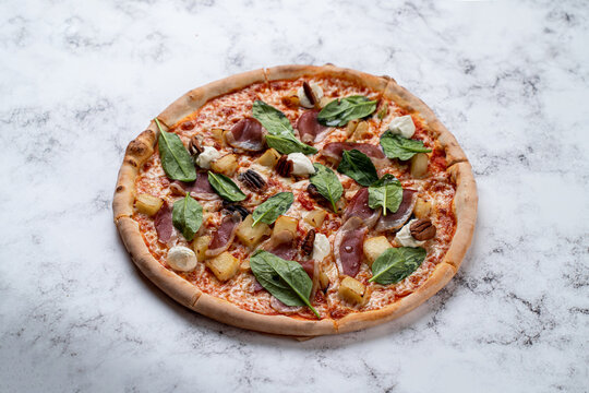 A beautifully crafted pizza emerges from a cozy European restaurant, garnished with savory meats, fresh spinach, and aromatic spices. The warm, inviting atmosphere complements the flavors