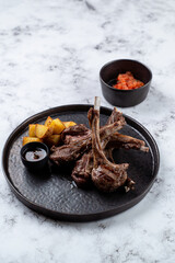 Experience a delightful culinary adventure at a European restaurant, savoring tender lamb chops alongside savory roasted potatoes and a vibrant dipping sauce, perfect for a satisfying meal
