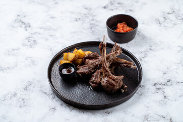 Enjoy a delightful meal featuring perfectly grilled lamb chops served with golden potatoes and a flavorful sauce, creating an unforgettable dining experience in a stylish European restaurant