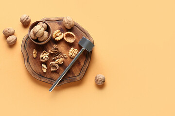 Wooden board of tasty walnuts on beige background