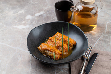 Savor the artistry of European cuisine with a beautifully plated fish dish, garnished elegantly and served alongside warm tea in a refined dining atmosphere