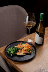Savor the blend of flavors in a gourmet dish featuring tender meat and fresh veggies, paired with a crisp white wine in an elegant dining setting that oozes sophistication
