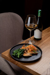 Delight in a carefully arranged plate of European cuisine, showcasing grilled fish, vibrant vegetables, and paired perfectly with a glass of white wine
