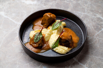 Savor the rich flavors of expertly prepared meat accompanied by velvety mashed potatoes, garnished with fresh greens. This European cuisine crafted with precision invites culinary exploration