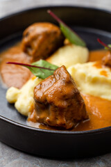 Hearty meatballs simmer in rich sauce, accompanied by velvety mashed potatoes, creating a delightful dining experience in a European restaurant. Perfect for food lovers seeking culinary adventure