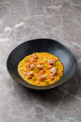 Diners enjoy a delightful plate of creamy shrimp risotto presented in a stylish black bowl. The dish features perfectly cooked shrimp and vibrant flavors, ideal for a special evening