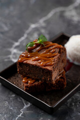Indulge in a decadent chocolate brownie topped with luscious caramel sauce, accompanied by a creamy scoop of vanilla ice cream. Perfectly plated for a memorable dining experience