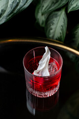 In a charming European restaurant, a vibrant red drink glistens in a glass with ice, adorned by a swirl of cream on top, creating a delightful and inviting atmosphere