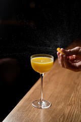 A skilled mixologist garnishes a vibrant yellow cocktail in a stylish glass, highlighting the creativity and precision involved in contemporary drink preparation