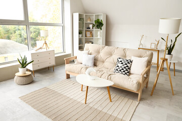 Interior of light living room with cozy sofa and white furniture