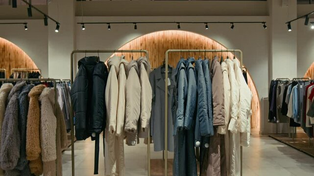 Tilt down no people view of trendy collection of womens jackets and coats hanging on racks in fashionable store