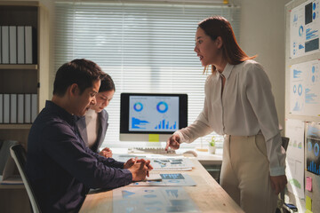 Businesswoman pointing at a document while expressing frustration during an office meeting,...