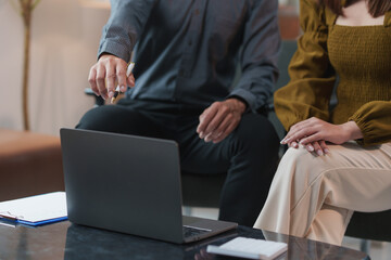Business colleagues are having a meeting and discussing work using a laptop, the businessman is pointing at the laptop screen with a pen and explaining something to his colleague