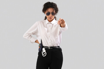 African-American female police officer pointing at viewer on white background