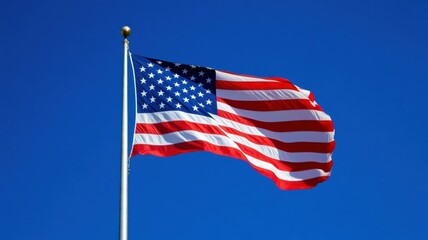 Fototapeta premium American flag waving against a clear blue sky during a sunny day