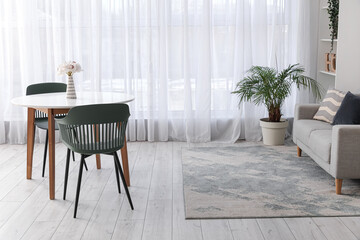 Interior of spacious living room with table, chairs, sofa, houseplants and shelving unit