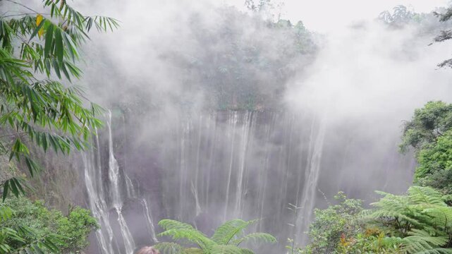 Tourist woman admiring majestic tumpak sewu waterfall in java