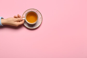 Female hand holding cup of green tea on color background