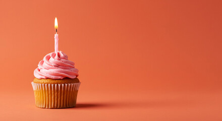 Delicious Pink Frosted Cupcake with Burning Candle on Orange Background