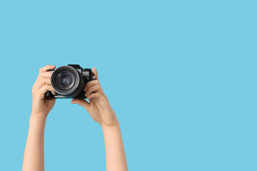 Female hands with modern camera on blue background