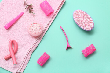 Towel with hair brushes, curlers and clips on turquoise background