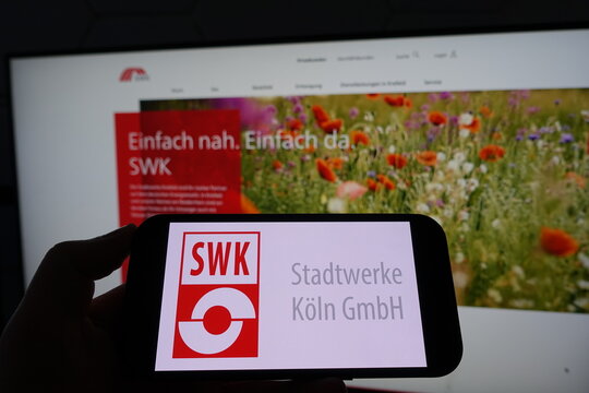 Kiel, SH, Germany March 19 2025 Smartphone with the logo of SWK Stadtwerke K&ouml;ln GmbH in front of a monitor featuring their business website with colorful background
