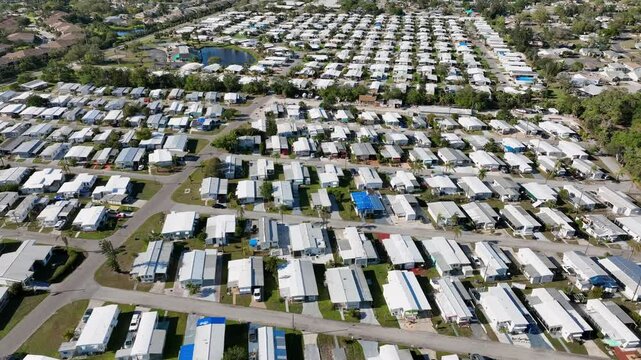 Dense populated mobile trailer homes in Bradenton, Florida. Sunny day in suburb of exotic town, USA. Aerial wide shot. Cheap housing area apartments in American city suburb.