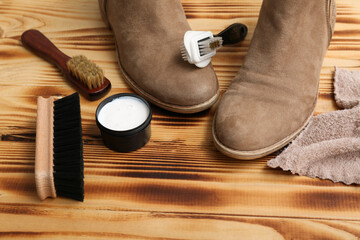 Boots, brushes and shoe polish on wooden background