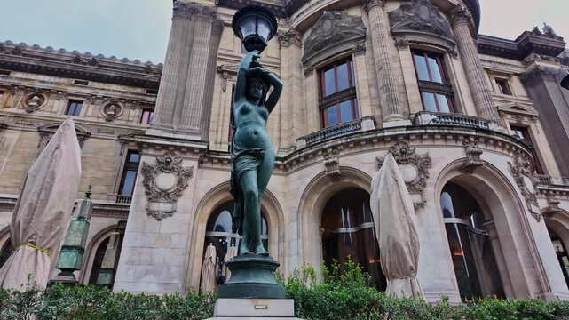 Lamp post outside Opera Garnier, bronze statue of woman, Paris in France. Low-angle pov
