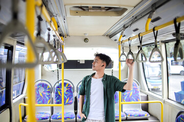 Smiling Young Man Holding onto a Handle While Commuting by Bus