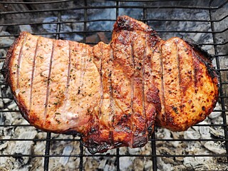 Large juicy pork loin steak marinated in a herb sauce, delicately roasted and grilled over hot coals