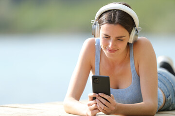 Woman wearing headphone using phone in a lake