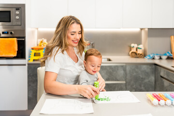 Mother and son painting with dot markers in kitchen